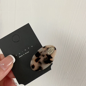 Handheld tortoiseshell acetate oval hair clip with gold metal tag and brand display card