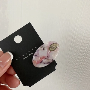 Pink marble acetate oval hair clip with small metal plate on black display card