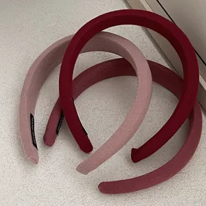 Close-up of three knitted berry-toned fabric headbands with soft ribbed texture and hand-made tags