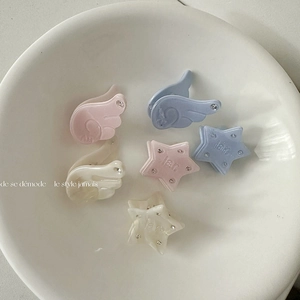 Star and angel wing hair clips in pink, blue, and white with rhinestones on a white plate