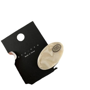 Oval acetic acid hair clip with marble texture and metal plaque on branding card