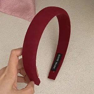 Detail of burgundy thick fabric headband with hand made label and textured cloth surface