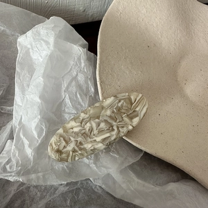 Detailed macro view of an oval acetate hair clip with premium marble textures in beige