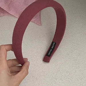 Detail shot of wide fabric headband in dusty rose showing woven texture and hand made label
