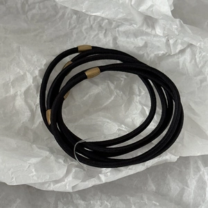 Detailed macro view of black elastic hair ties featuring cylindrical gold metal connectors