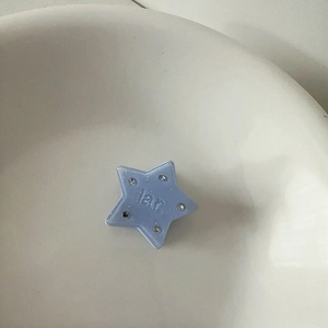 Close-up of light blue star hair clip with rhinestone accents and embossed lettering