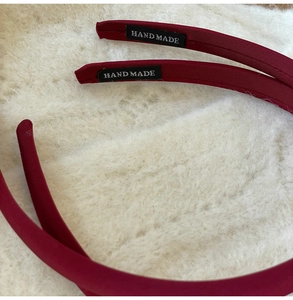 Détail de serre-têtes en tissu bordeaux avec étiquettes faites main sur fond en peluche