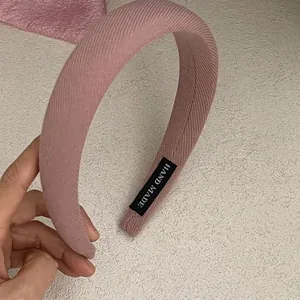 Close-up of a thick pink fabric headband featuring a stitched black Hand Made label inside
