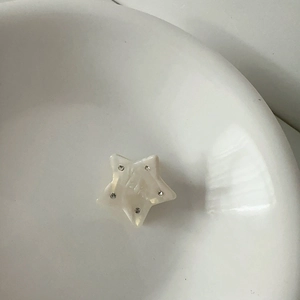 Detailed macro view of pearlescent star hair claw clip with crystal rhinestones
