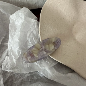 Detail of acetate oval hair clip showing purple marble texture and France made engraving