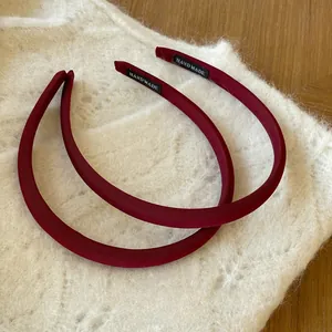 Détail de deux serre-têtes faits main en satin bordeaux avec étiquette HANDMADE sur tricot