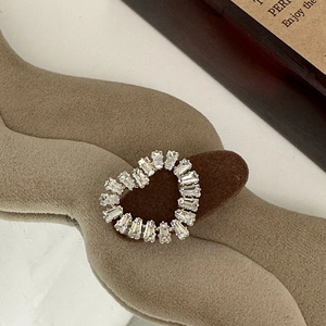 Macro shot of silver baguette-cut crystal heart jewelry on beige textured velvet