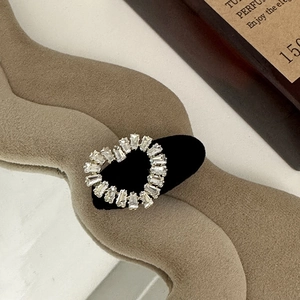 Detail of heart-shaped rhinestone hair clip with baguette-cut crystals on black base