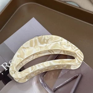 Detail of acetate crescent hair claw clip with marble texture on a brown tray