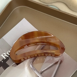 Detail of a brown tortoiseshell acetate hair claw clip with Creation France gold lettering