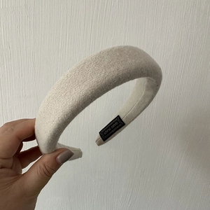 Detail of beige chunky knit headband showing textured fabric and Hand Made woven label