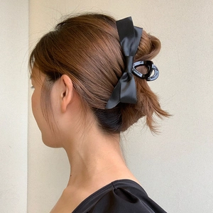 Pince à cheveux élégante avec nœud en satin noir montrée sur un modèle de vue latérale