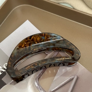 Detail of a tortoiseshell acetate hair claw with gold Creation France logo text