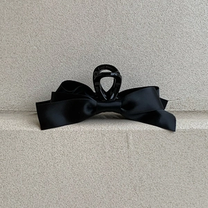 Détail d'une pince à cheveux à nœud en satin noir montrant la texture du tissu soyeux