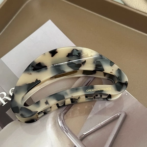 Detailed close-up of acetate crescent hair claw with tortoiseshell pattern and gold logo