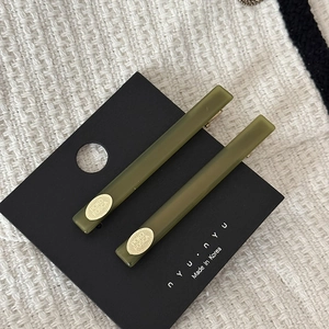 Detailed macro view of olive green acetate hair clips on black display card texture