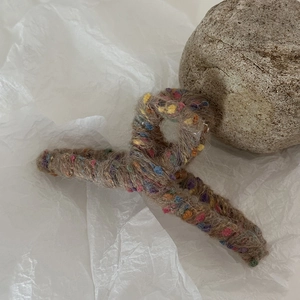 Dettaglio della pinza per capelli in maglia marrone con trama di filato a pois