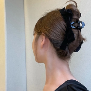 Pince à cheveux élégante avec nœud en satin noir présentée sur un modèle de profil