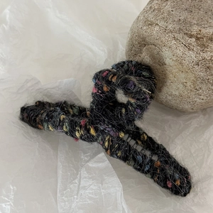 Dettaglio della trama in tweed arcobaleno su un grande fermaglio per capelli nero