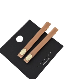 Pair of matte acetate hair clips in milk tea brown color with golden metal oval nameplate