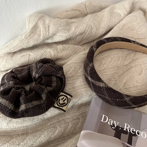 Close-up of brown plaid scrunchie and headband set on a cozy knit sweater background