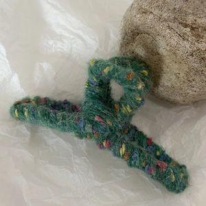 Primo piano di una grande clip per capelli in maglia verde con texture a pois colorati