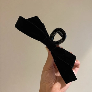 Détail de la grande pince à cheveux avec nœud en satin noir et dents robustes polies