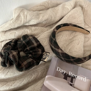 Close-up of British style plaid headband and scrunchie set on a beige knit fabric background