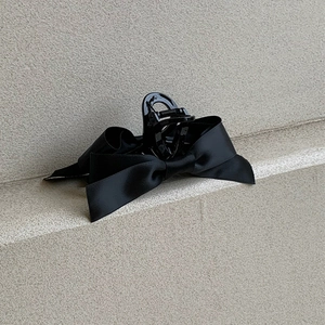 Détail d'une pince à cheveux à nœud en satin noir montrant la texture du tissu