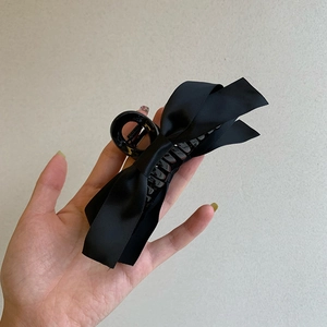 Détail de la pince à cheveux noeud en satin noir montrant le tissu et le mécanisme