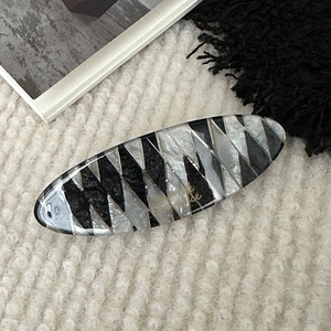 Detailed view of oval acetate hair clip with black and white geometric marble texture