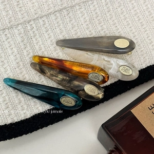 Detail of five colorful marble texture acetate hair clips on elegant white tweed background