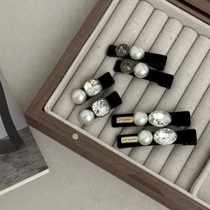 Détail de barrettes en velours avec perles, strass et étiquette Lovedays dans un coffret