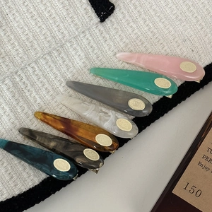 7-piece set of water-drop acetate hair clips in various colors with gold metal logo detail