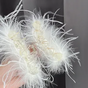 Macro view of white ostrich feather hair claw clip with transparent base and metal spring