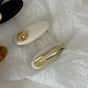 Minimalist acrylic hair clip set in ivory, black, and amber on textured white paper