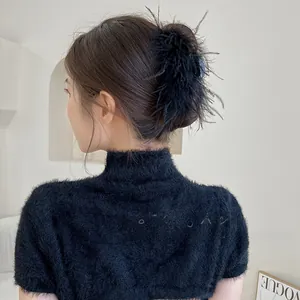 Detail showing elegant black ostrich feather hair claw clip worn on a bun hairstyle