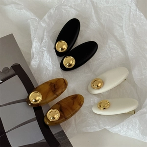 Retro acrylic oval hair clips in black, cream, and amber marble with gold accents