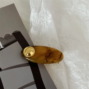 Minimalist oval acrylic hair clip with tortoise shell pattern and gold metal accent