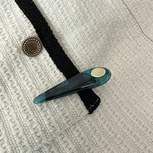 Detail view of a dark green resin hair clip with marble texture and gold metal plate