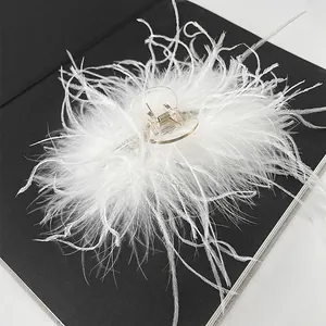 Close-up of white ostrich feather hair claw clip with transparent base on a black book