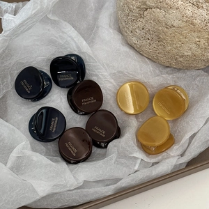 Mini round acetate hair claws in dark blue, brown, and amber with gold lettering