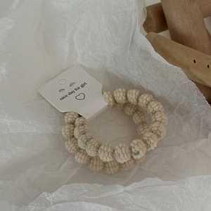Detail of beige popcorn textured elastic hair ties on minimalist paper packaging card