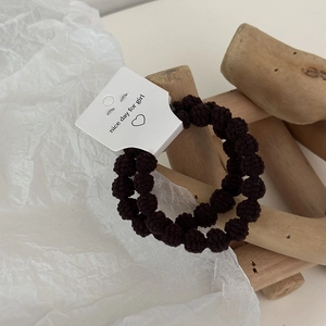 Detailed view of elastic dark brown textured knit hair bands on a white hanging card