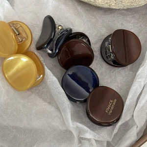 Detailed macro view of mini acetate hair claws in various elegant colors with gold lettering